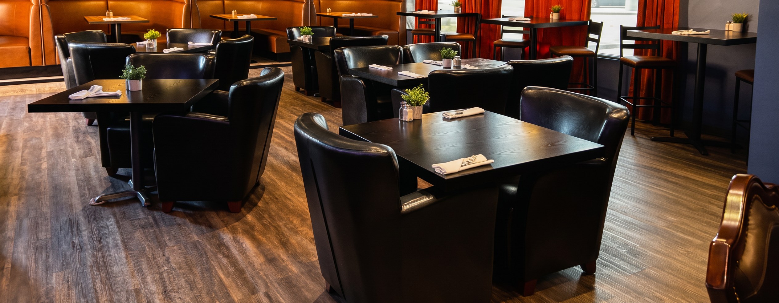 The dining room at Lighthouse Community Eatery — leather booths, warm pendant lighting and set tables